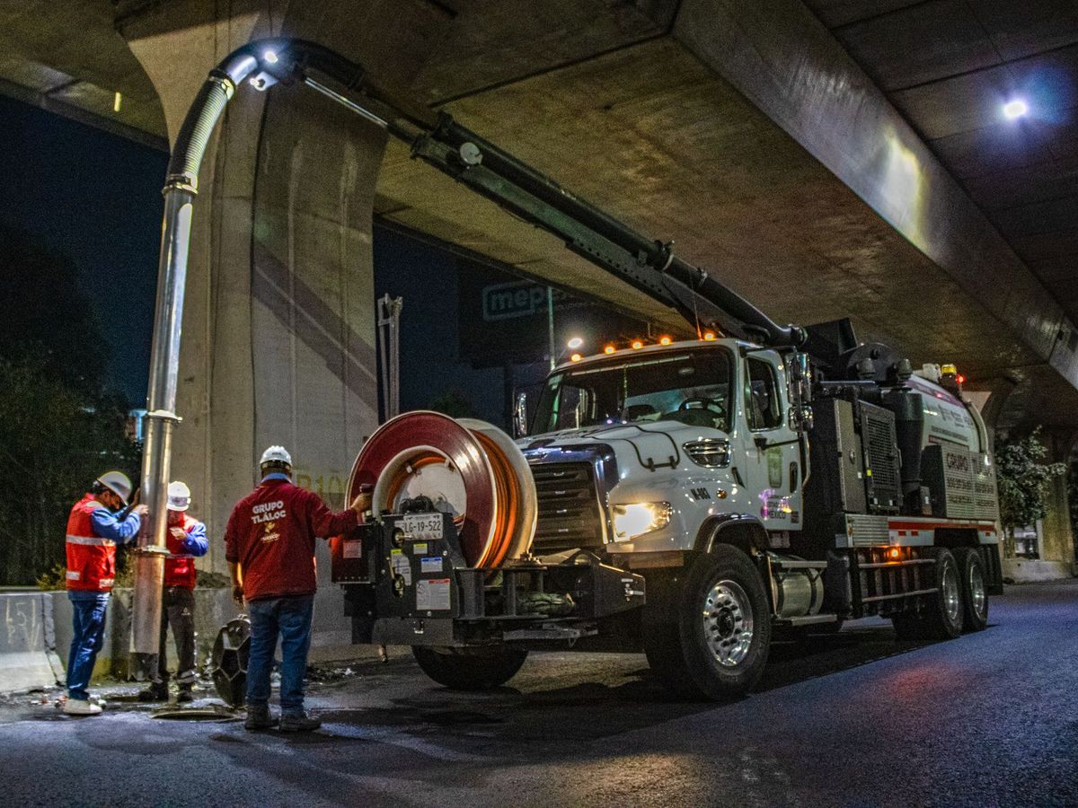 A crew working beside a vacuum truck at night